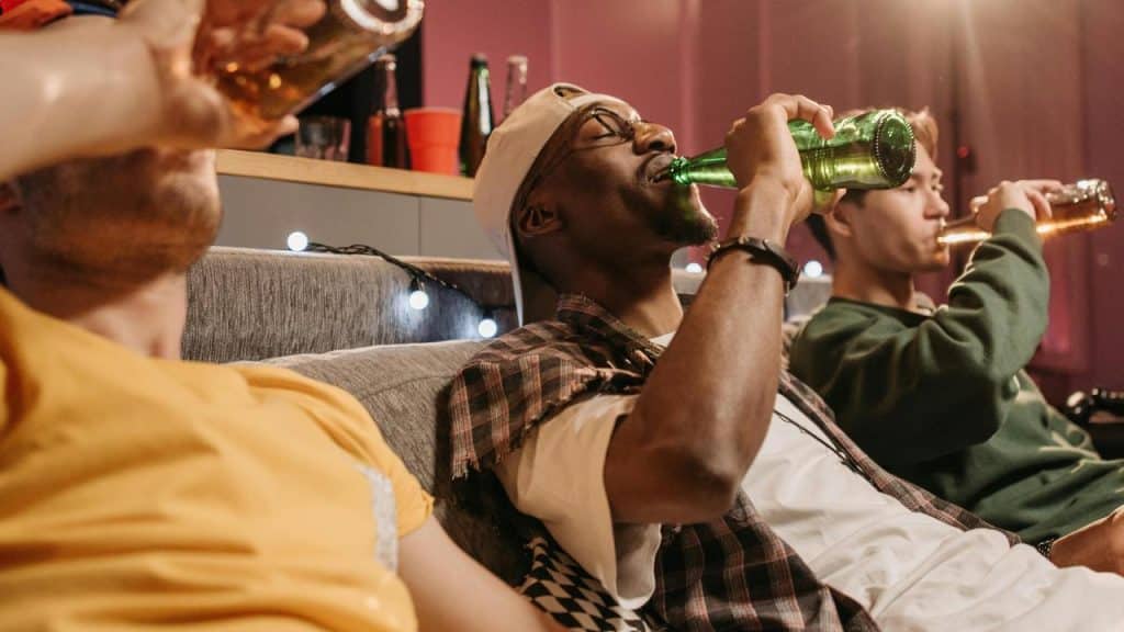 A group of friends sitting on a couch drinking beer.