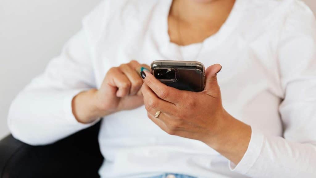 A woman in a white shirt using a smartphone.