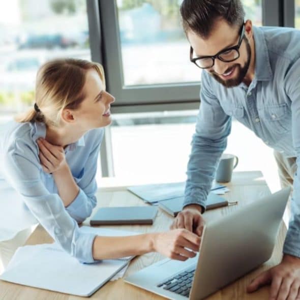 Woman smiling warmly at a man at work while he looks slightly unsure