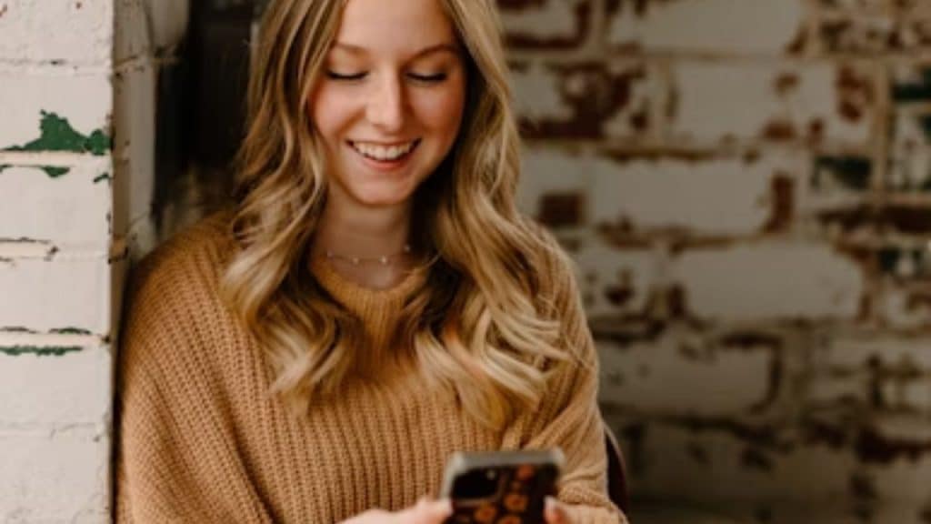 Woman smiling at her phone while texting back quickly