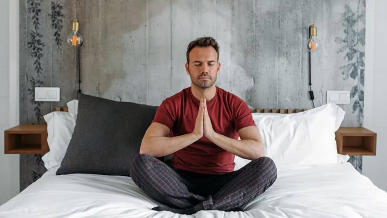 A man meditating in his bedroom.