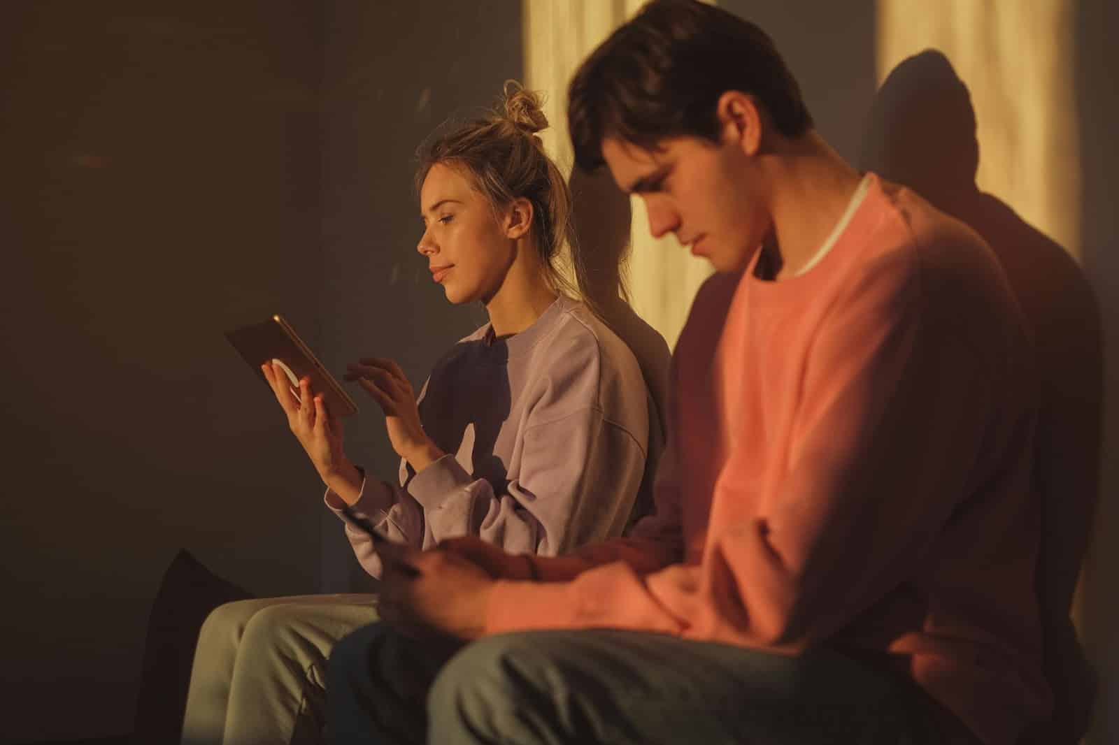 A man and woman using their own gadgets.