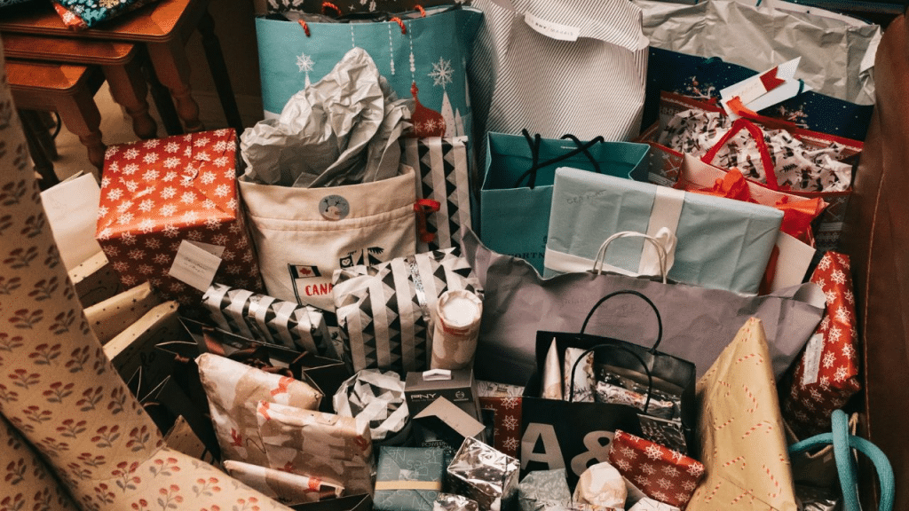 A chaotic pile of many wrapped presents and gift bags with paper.