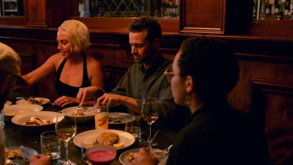 A group of friends at a dinner table, avoiding eye contact with one partner