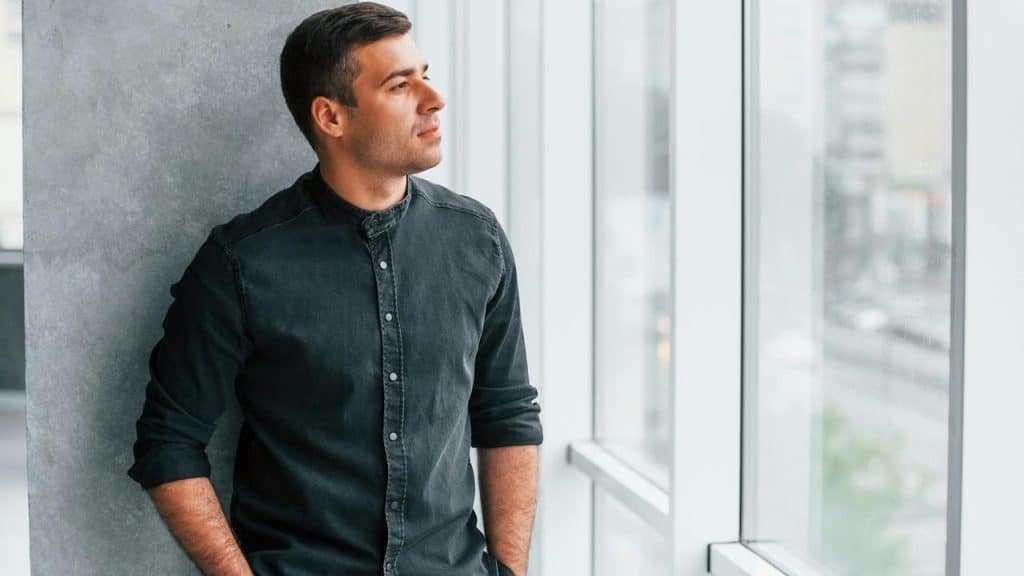 A man in a dark shirt looking out a window.