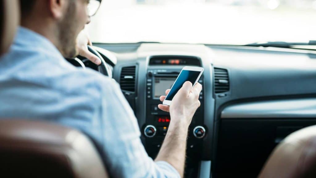 A man driving while holding a smartphone.
