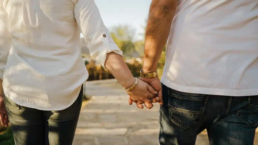 A couple holds hands while walking outdoors.
