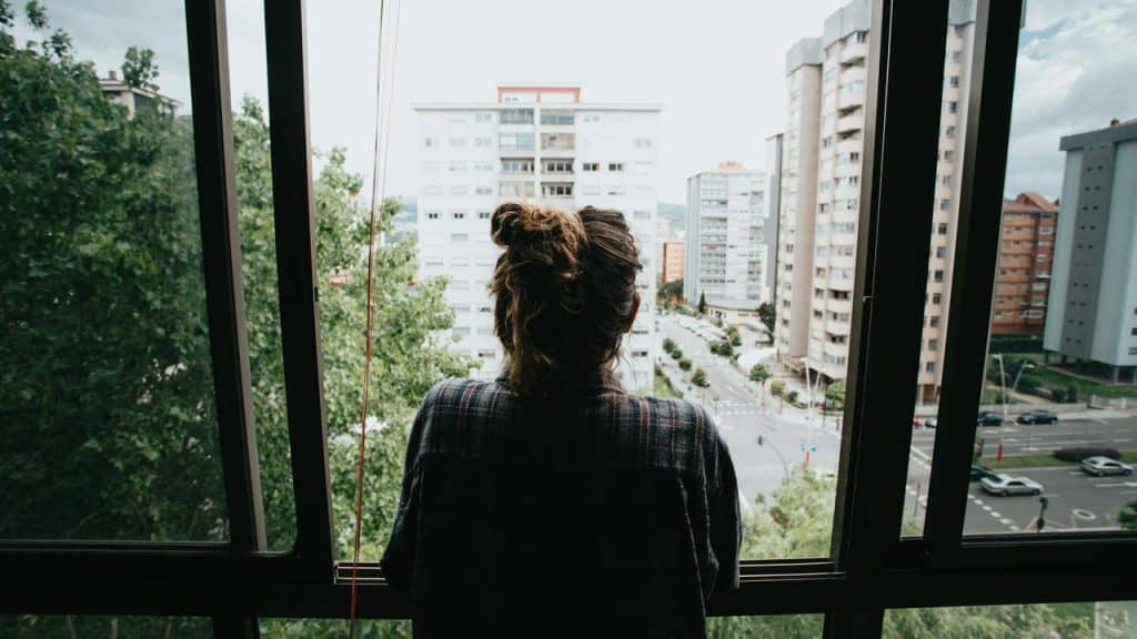 A woman looking out of a window at city buildings.