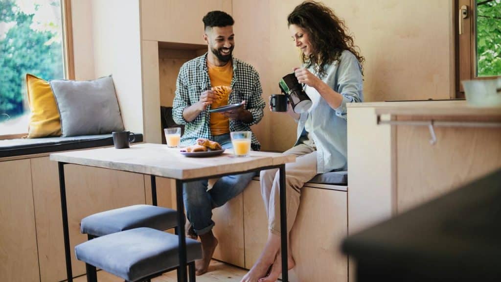 A couple enjoying breakfast together at a small kitchen table.