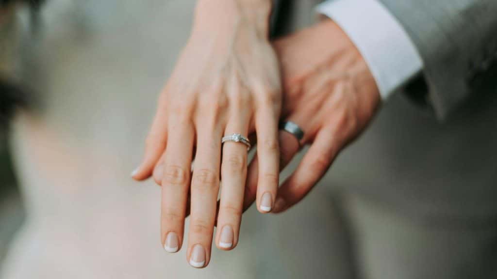 A close-up of a couple’s hands wearing wedding rings.