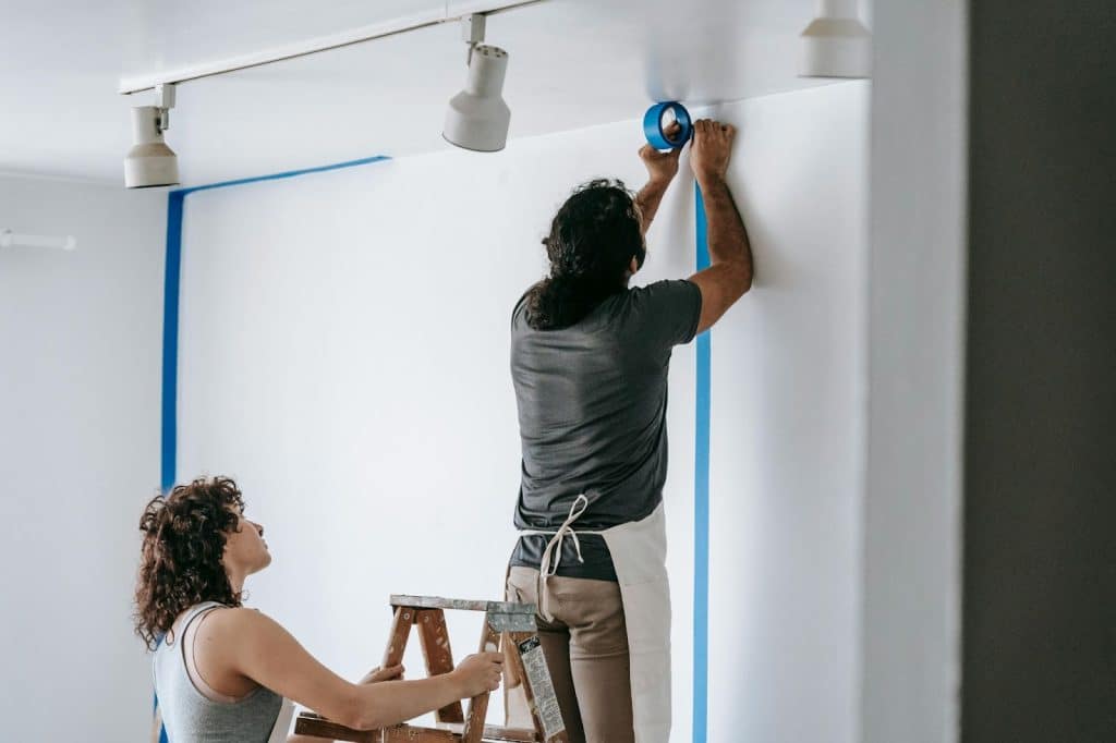 A man and woman decorating a room for their baby