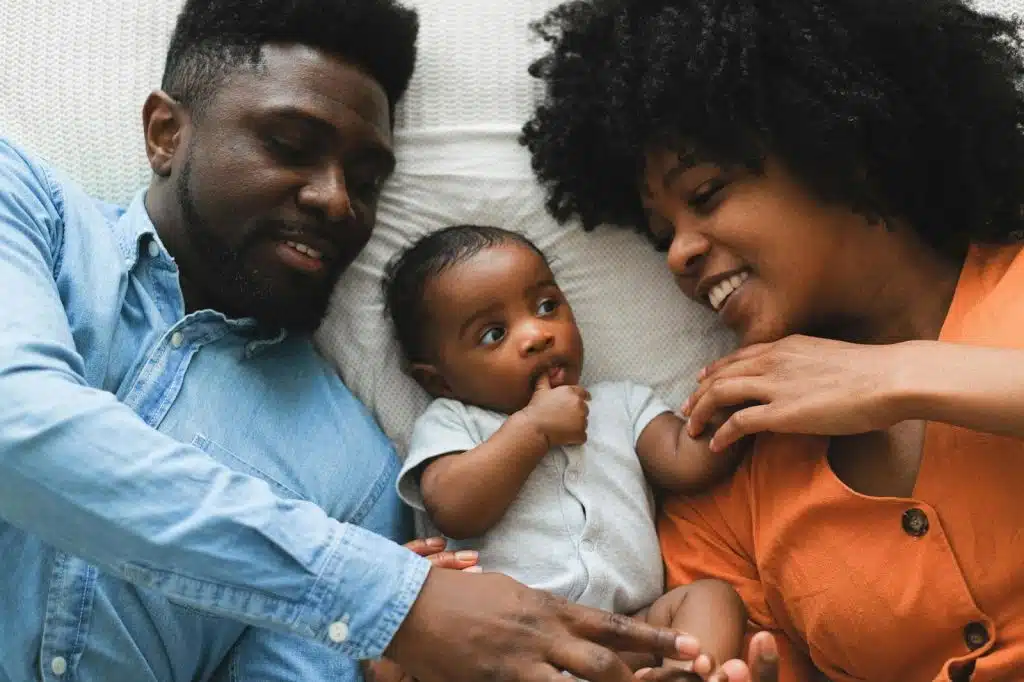 A man and woman laying on the floor with their baby