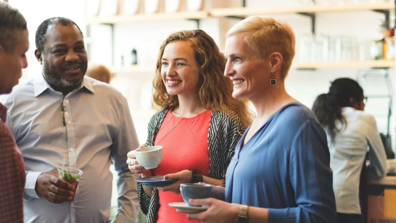 A diverse group of friends socializes while holding beverages at a casual gathering.
