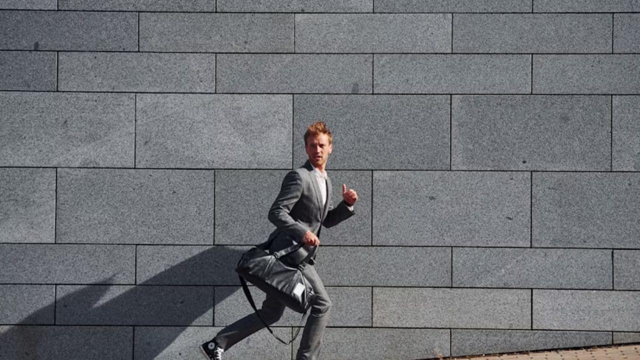 Man running after work while  holding his gym bag.