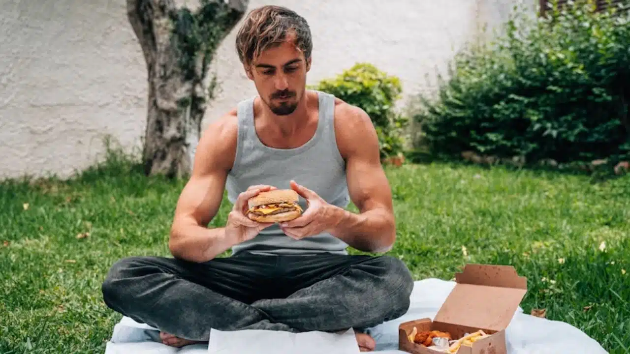 Man eating fast food at his desk while looking exhausted.