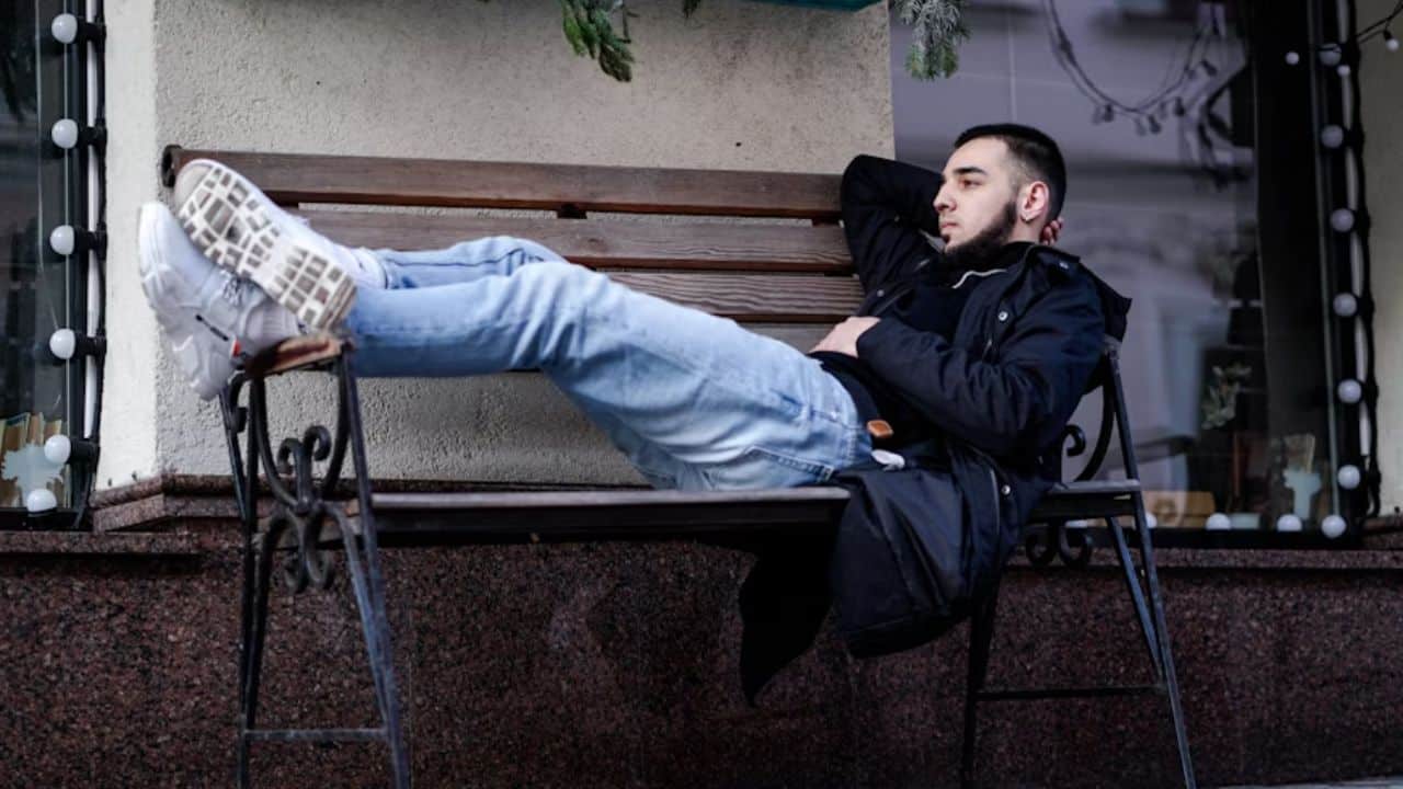  Man sitting alone on park bench looking emotionally drained.