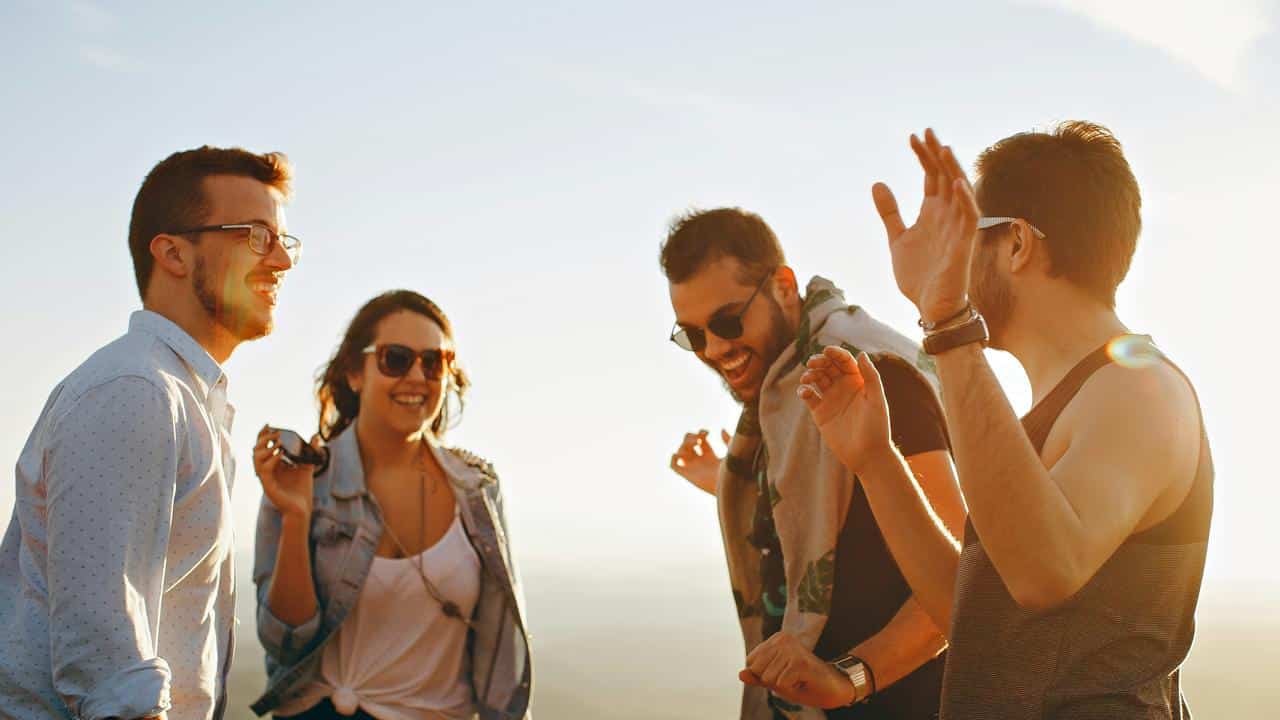 A group of friends laughing and enjoying time together outdoors at sunset.