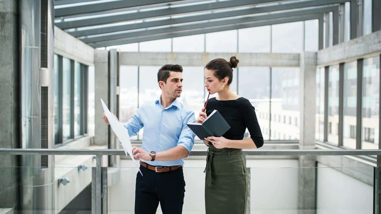 A man and woman discussing documents in a modern office building.