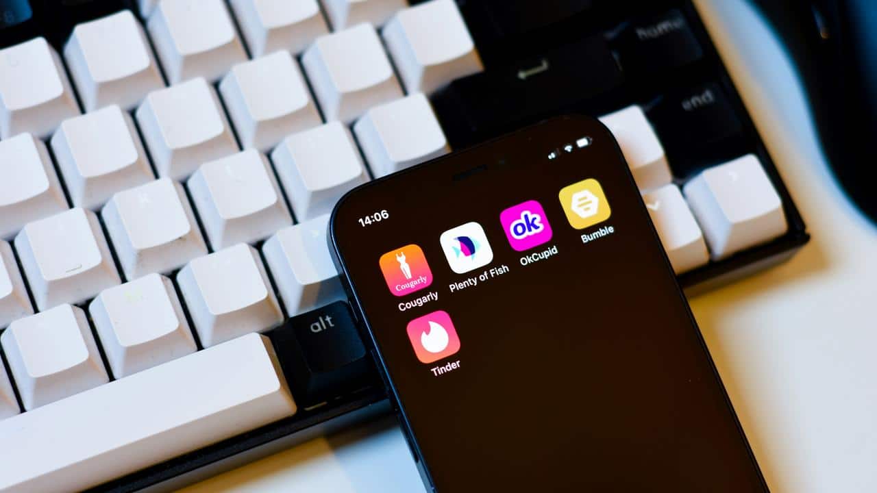A smartphone showing dating apps on the screen placed next to a keyboard.