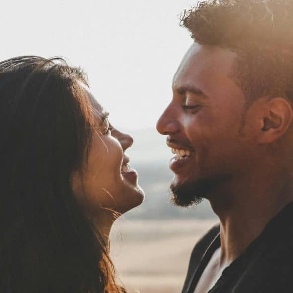 A couple smiling at each other outdoors.