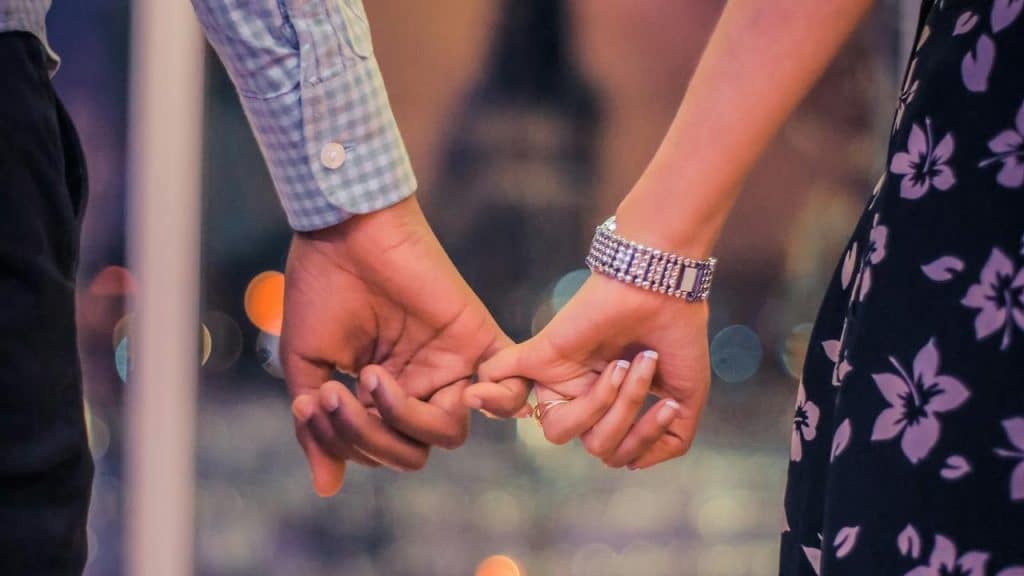 A couple holding hands with fingers intertwined.