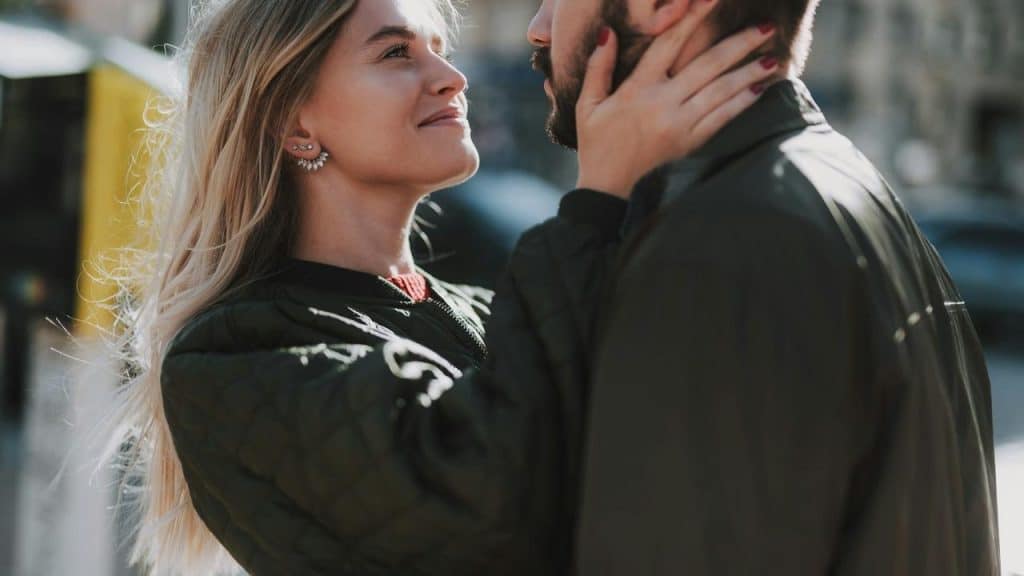 A woman smiling while holding a man's face affectionately.