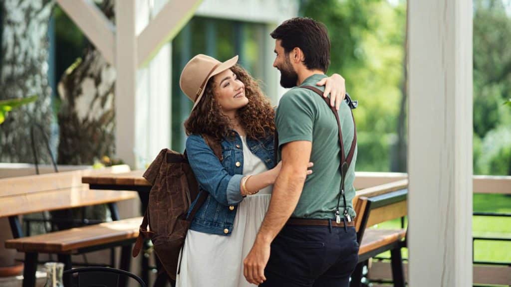 A smiling couple embracing outdoors near a café.