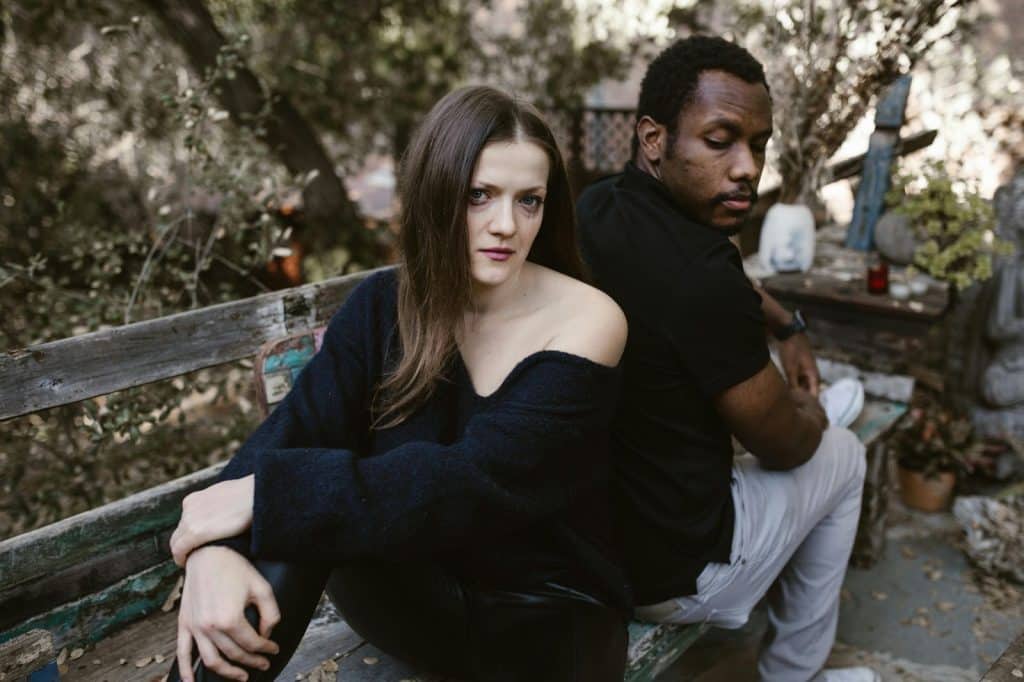 A man and woman sitting at the bench facing away from each other