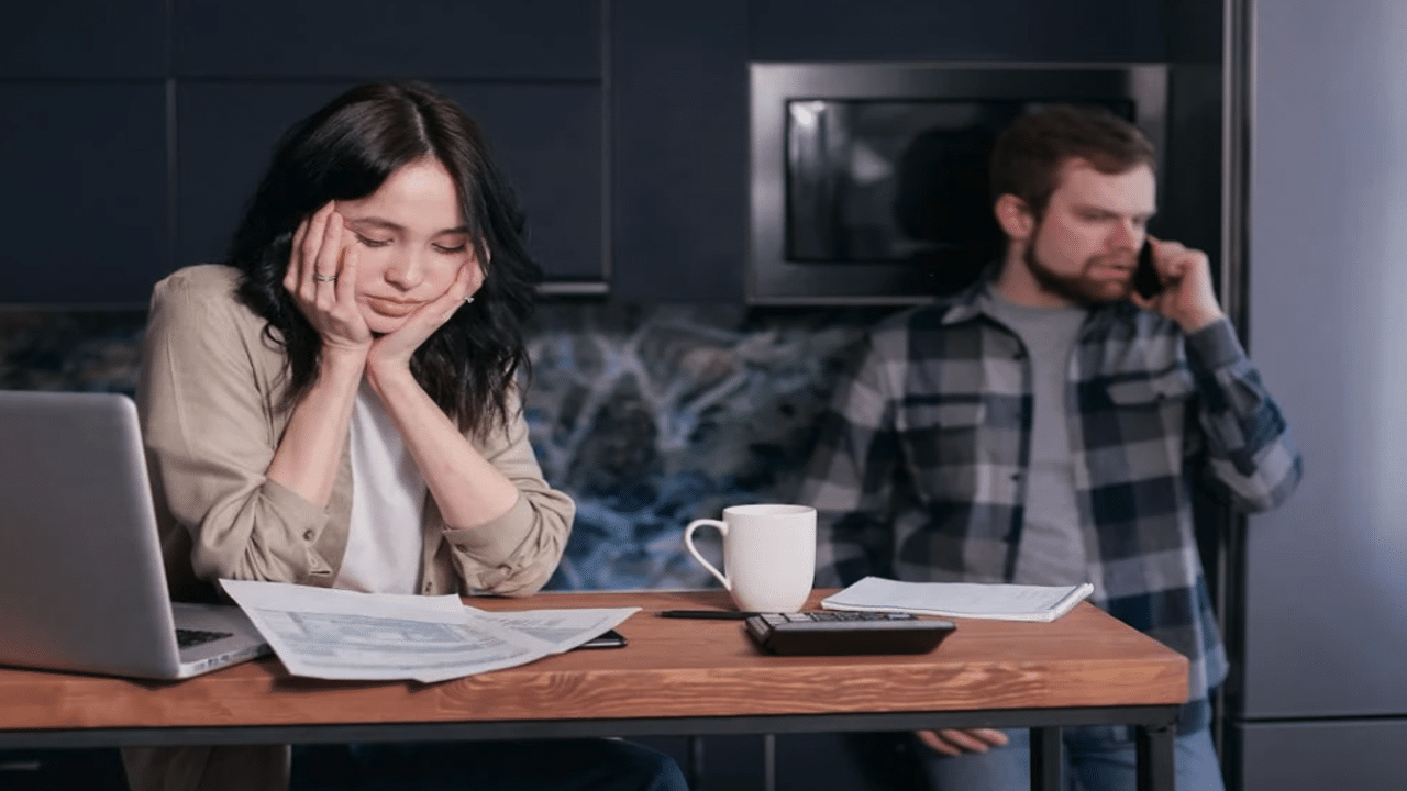 A man ignoring his wife while she works.