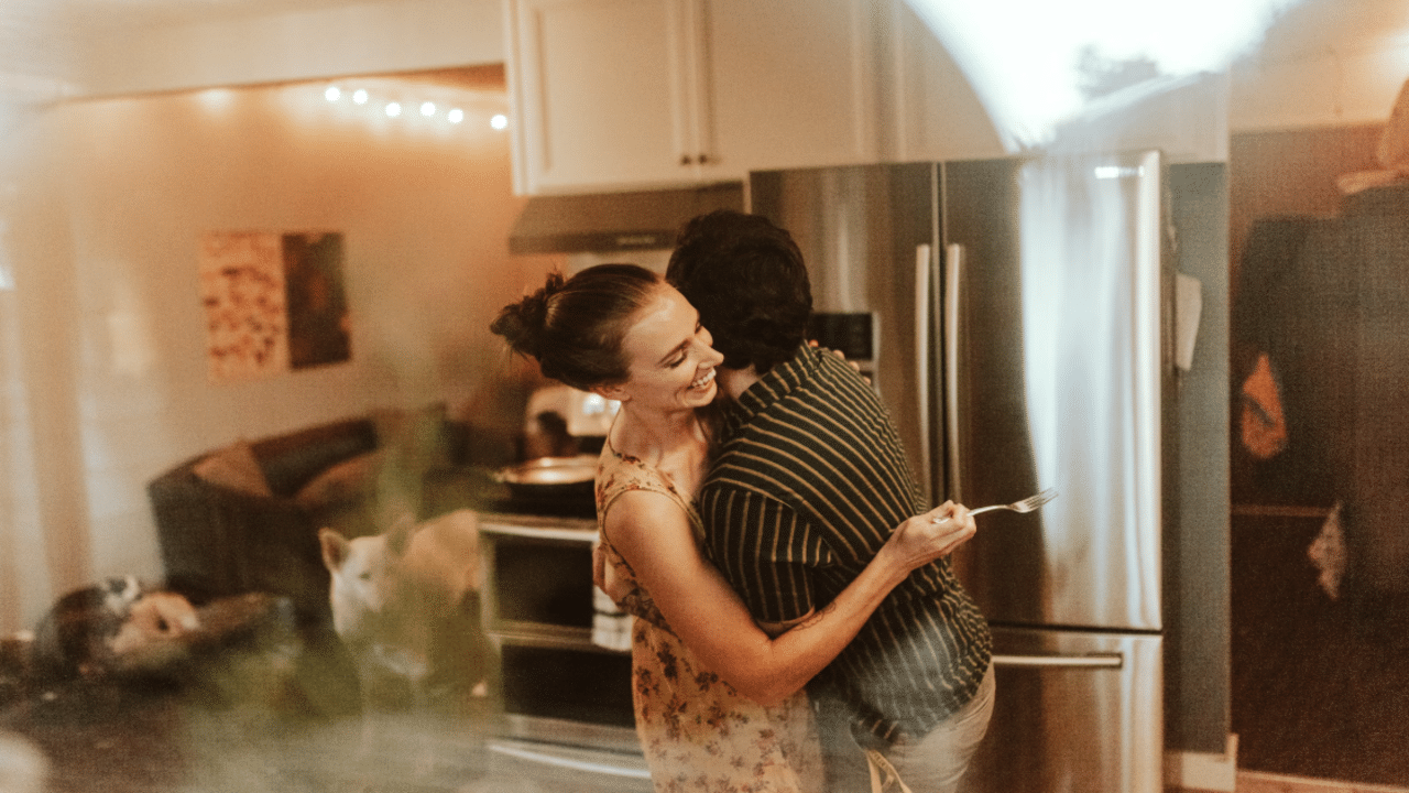 A couple hugging in the kitchen.