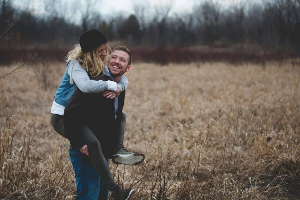 A man carrying a woman on his back while laughing