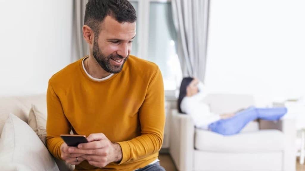 A woman looking distant while her partner stares at his phone