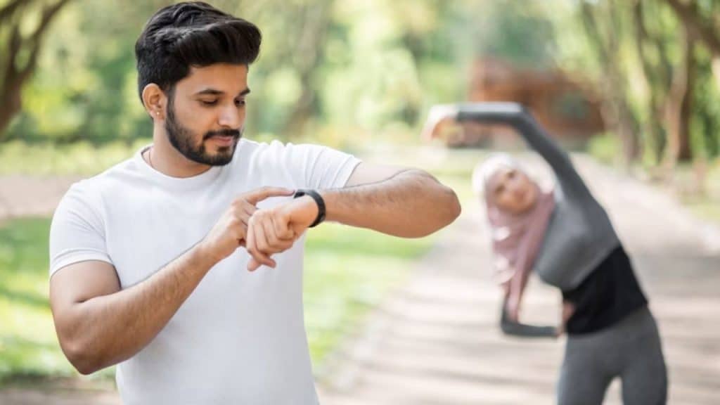 A man ignoring exercise while his partner stretches outside.