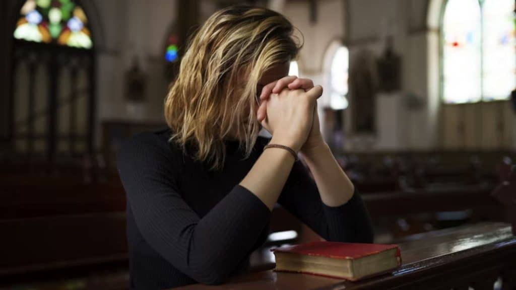 A woman praying in church without her partner