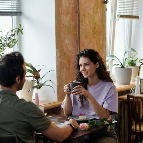 A man and woman talking at a café table.