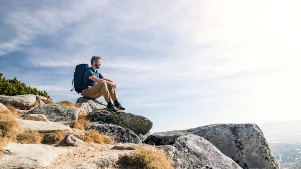 Man practicing deep breathing exercises on top of the mountain