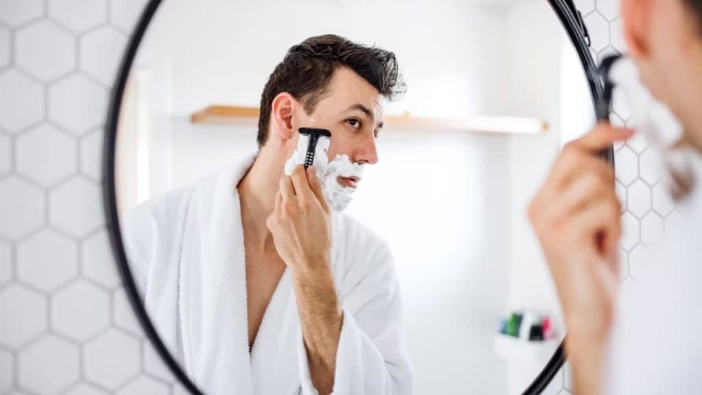 Man grooming in front of bathroom mirror