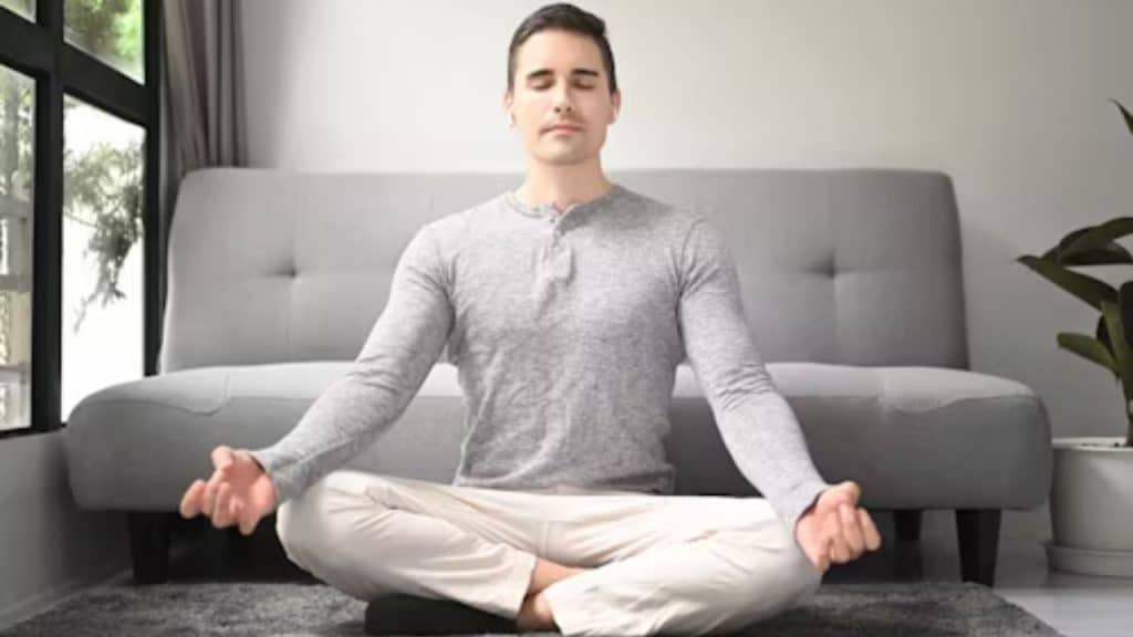 Man meditating on yoga mat indoors