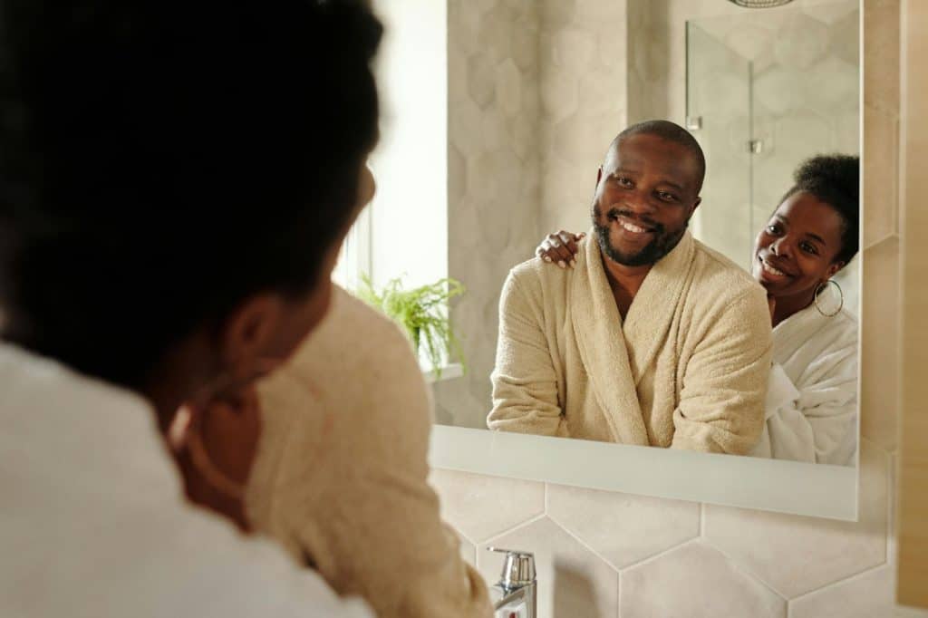 A man and woman looking at the mirror