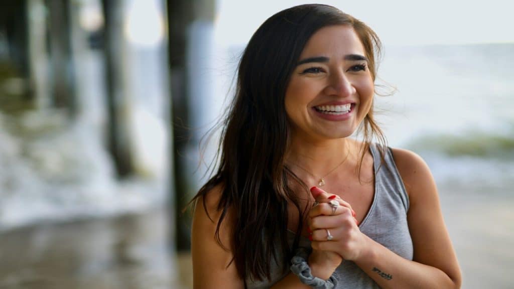 A woman smiling by the beach 