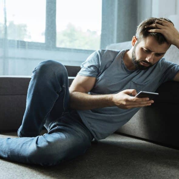 A man looking upset at what he’s seeing on his phone