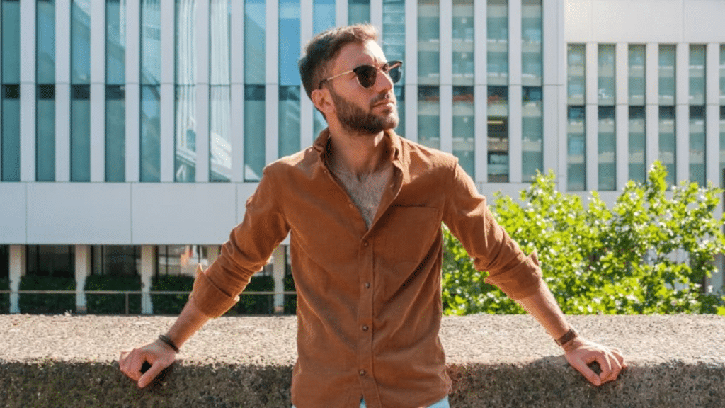 A confident man standing near the street in a casual but sharp outfit, exuding calm confidence.