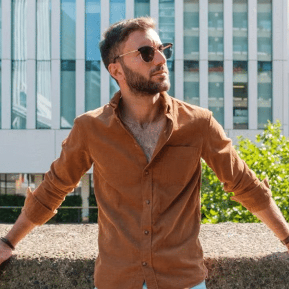 A confident man standing near the street in a casual but sharp outfit, exuding calm confidence.