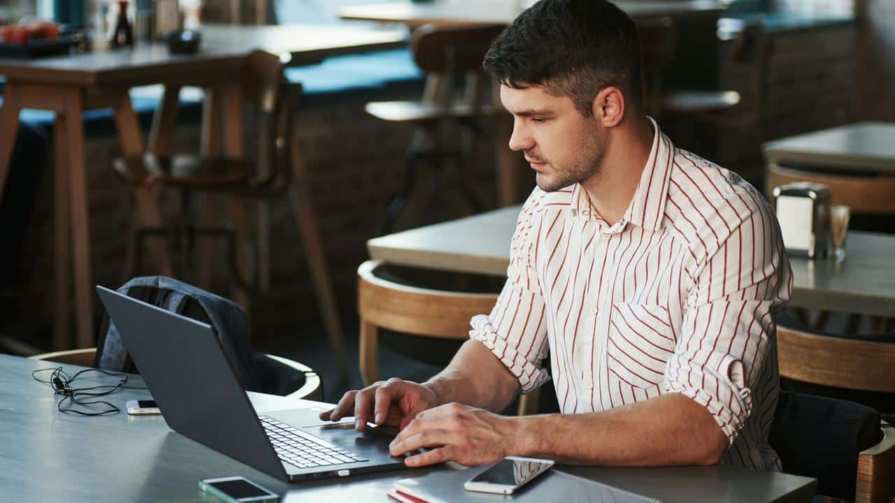 A man working on a laptop at a café table.