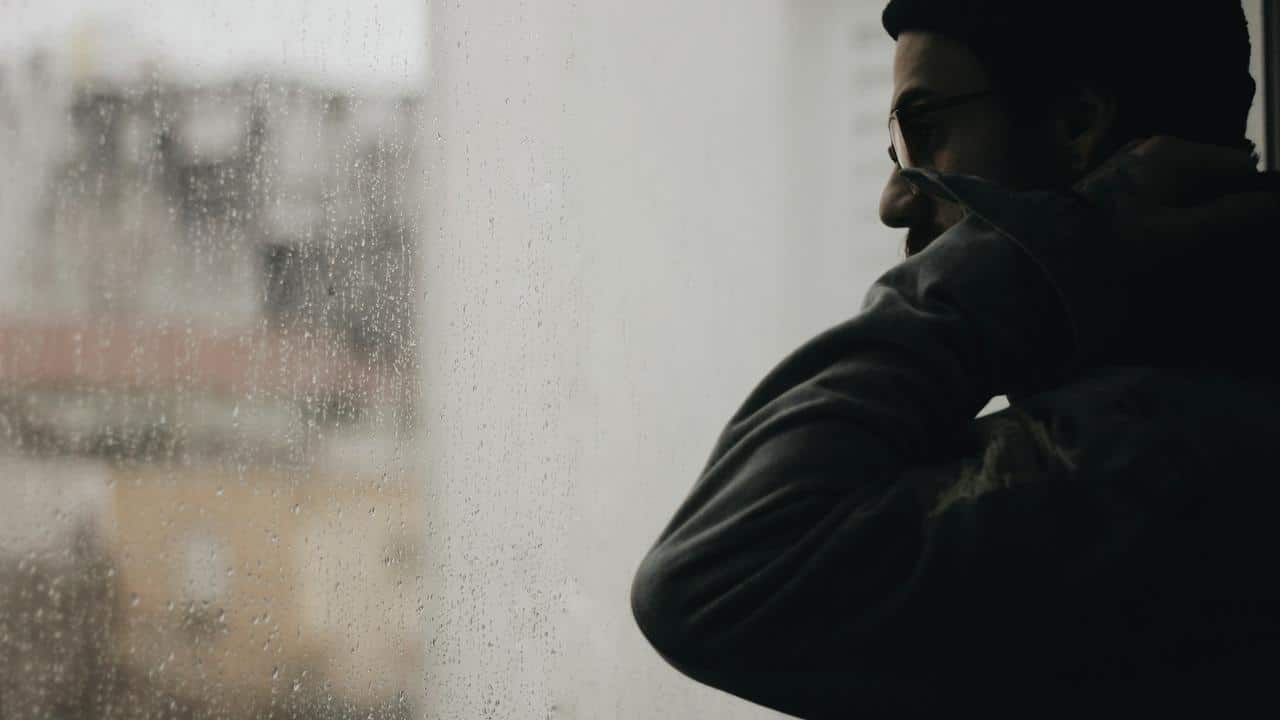 A man looking out a rain-covered window.