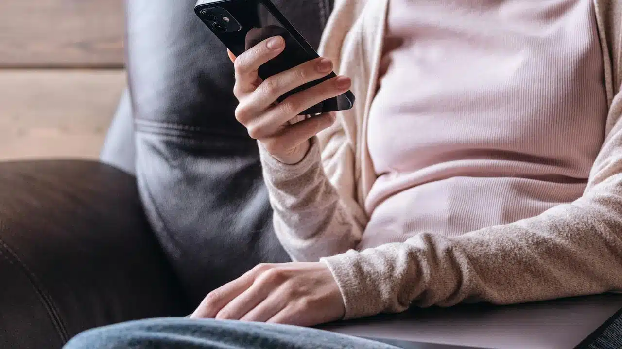 A person sitting on a couch holding a smartphone.