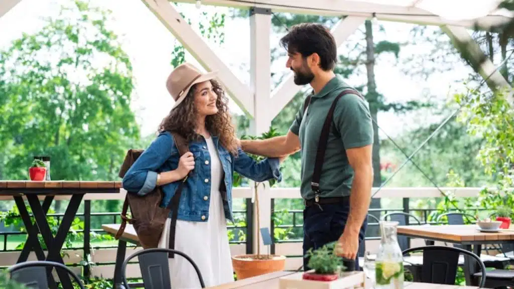 Man greeting a woman with a big smile at a restaurant entrance