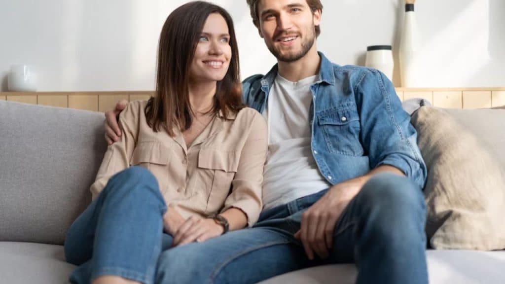 Couple sitting side by side on a couch with relaxed distance