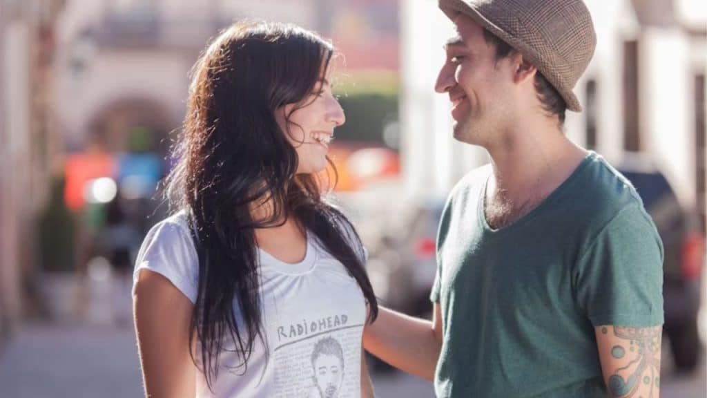 Couple smiling warmly while saying goodbye outside