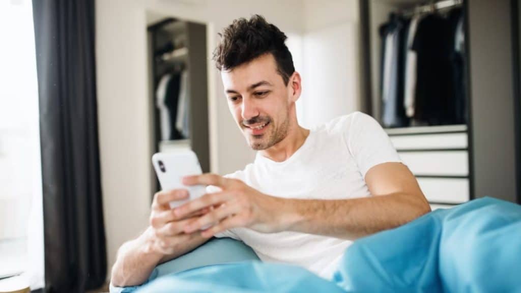 Man texting on phone with a smile the morning after a date